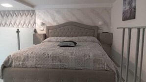 A bed with a patterned bedspread and a single pillow, a wall-mounted light, and a painting on the wall. - Central Station House (Naples)