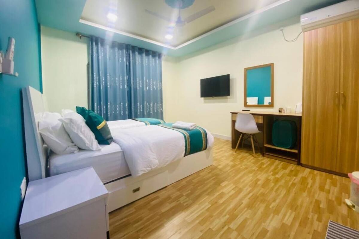 Habitación de hotel con cama, escritorio, silla, televisor y armario.