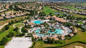 An aerial view of a resort with multiple swimming pools, a golf course, and residential areas in the background. - ChampionsGate Luxury 8BR Villa, Pool, Theater, Game Room (Four Corners)