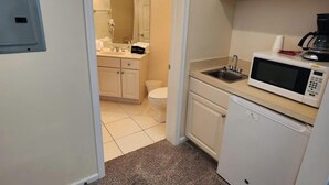 A compact kitchen with a microwave, sink, and a small refrigerator. - Right Direction Rentals Studio Villa 8270 (Port St. Lucie)