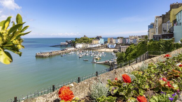 A coastal town with a harbor filled with boats, a pier, and colorful buildings along the waterfront. - No 10 Croft House (Tenby)
