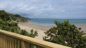A beach with a wooden railing, trees, and a distant view of the sea. - No 10 Croft House (Tenby)