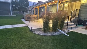 A residential backyard with a patio, outdoor furniture, and a well-maintained lawn. - Spacious 5-bedroom house in beautiful Anaconda with Salt water Hot Tub (Anaconda)