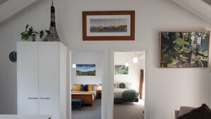 Habitación amplia con cama, escritorio y silla. Se observa un armario, un cuadro y un reloj en la pared.