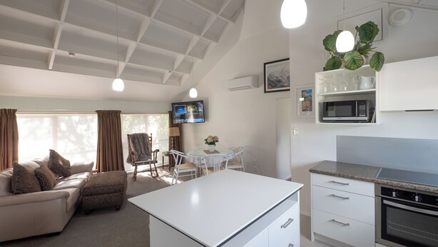Una sala de estar moderna con sofá, mesa de comedor y zona de cocina con microondas y horno.