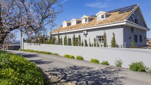 A two-story house with a sloped roof, solar panels, and a small attached garage.