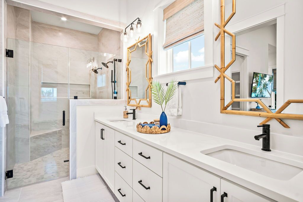 A modern bathroom with a large mirror, a vanity with drawers, and a shower area.