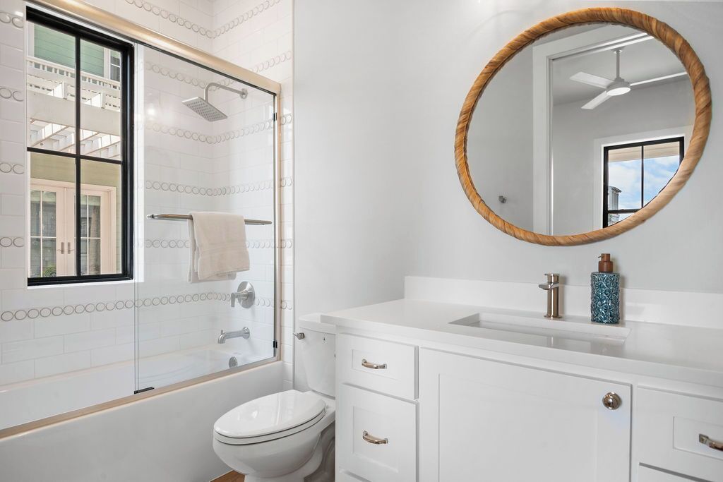 Un bagno moderno con doccia vetrata, un WC bianco e un mobile lavabo con specchio rotondo.