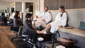Un spa moderne doté d’un espace d’accueil, de sièges pour les clients et d’un grand mur entièrement recouvert de miroirs.