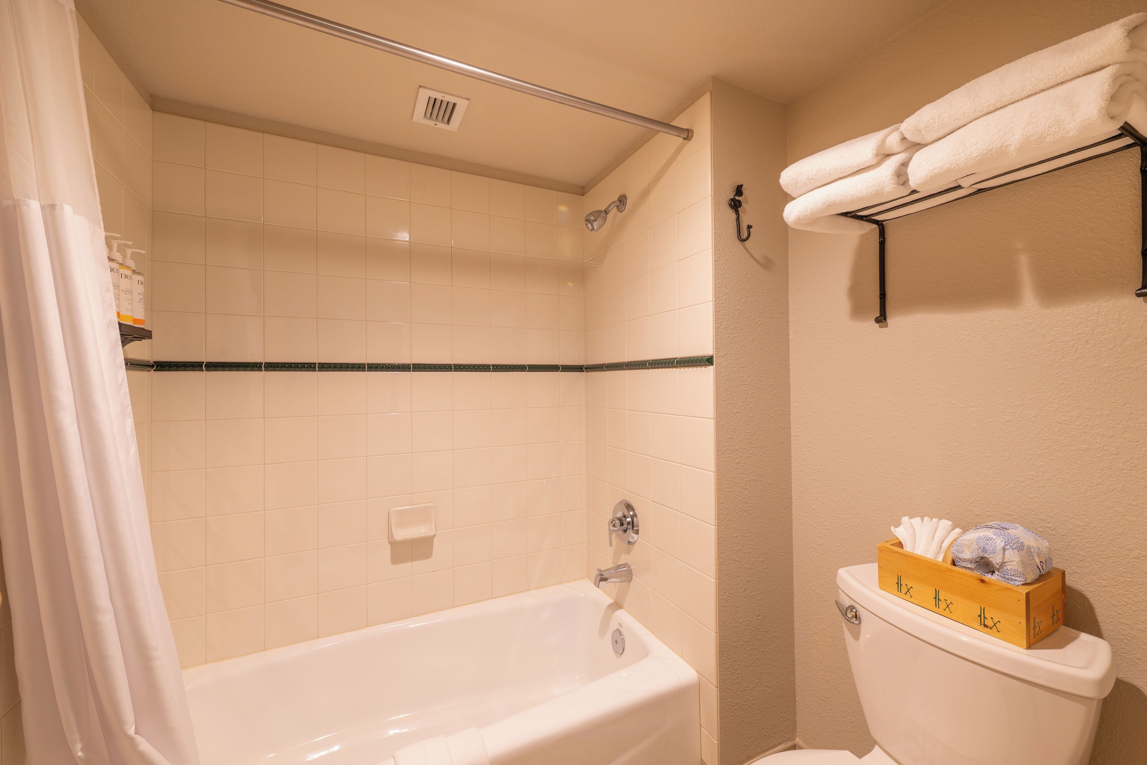 A bathroom with a bathtub, toilet, and a shelf with towels.