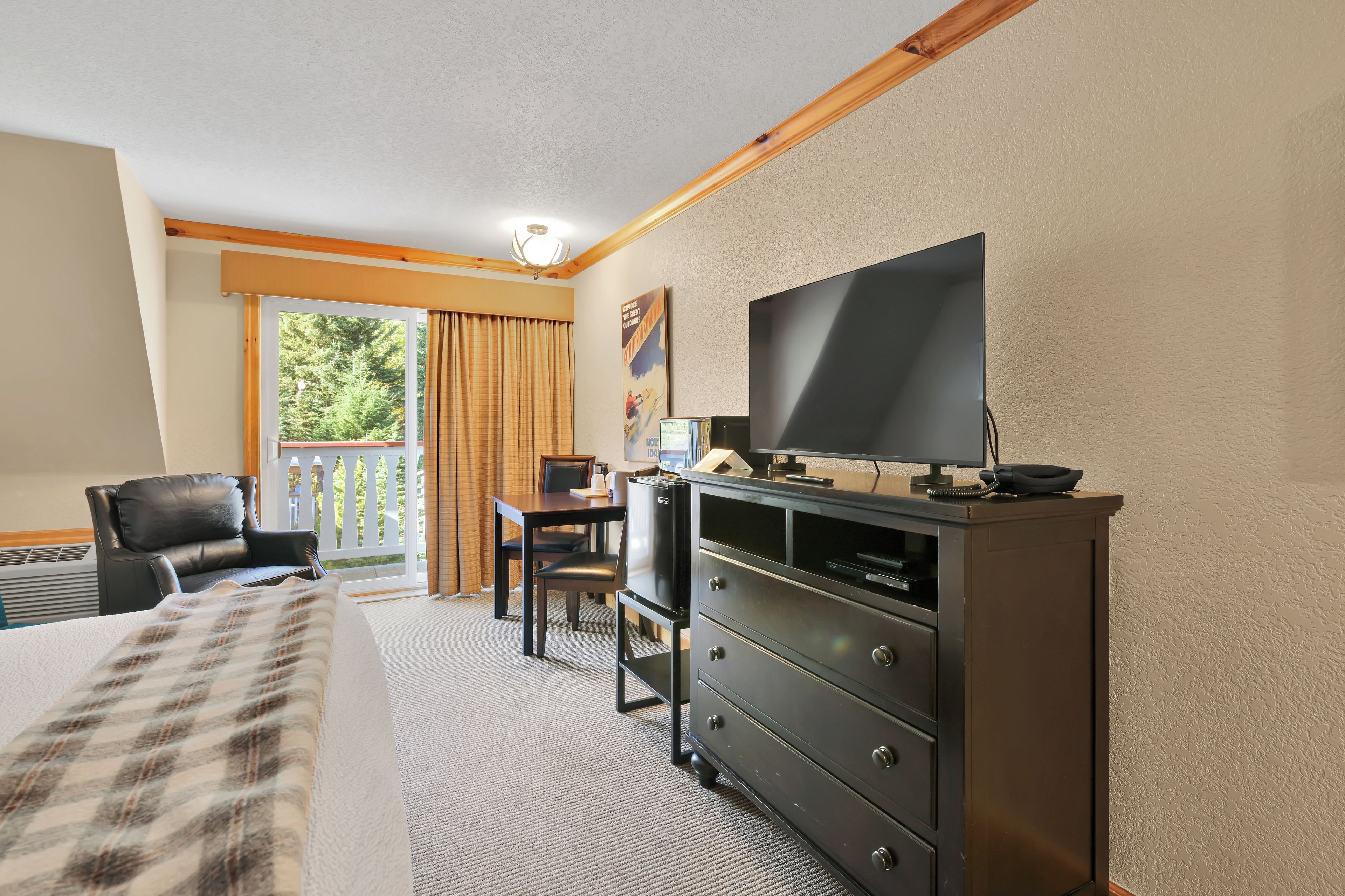 A hotel room with a bed, a desk, a chair, a television, and a dresser.