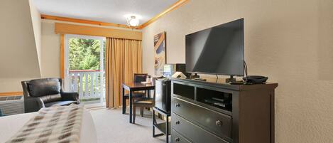 A hotel room with a bed, a desk, a chair, a television, and a dresser.