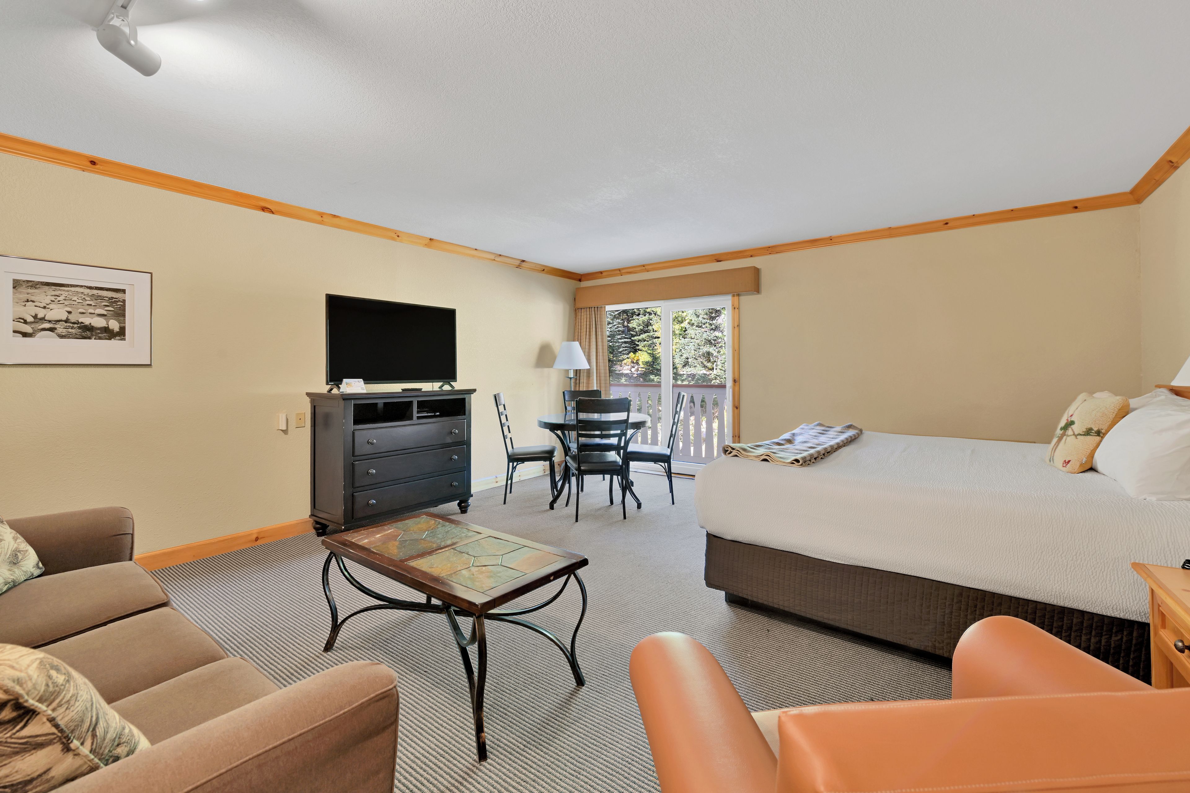 A hotel room with a bed, a desk with a chair, a television, and a sofa.
