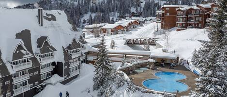 A ski resort with multiple buildings, a pool area, and snow-covered surroundings.