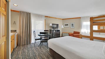 Una habitación de hotel con una cama grande, un escritorio con silla, un televisor y un sofá.