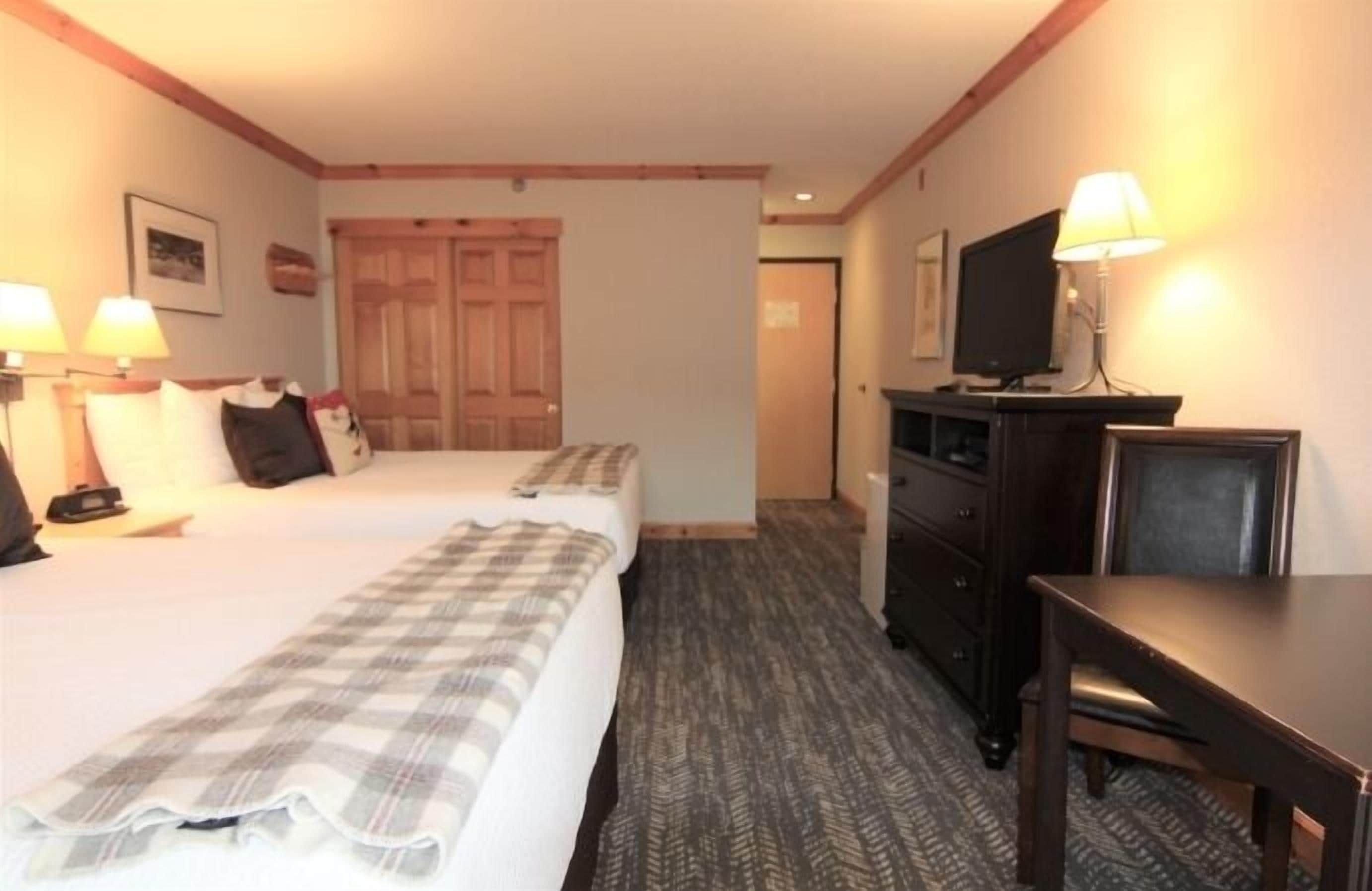 A hotel room with a bed, a desk, a television, and a wardrobe.