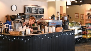 Un comptoir de café avec un tableau affichant le menu, des machines à café et divers condiments.