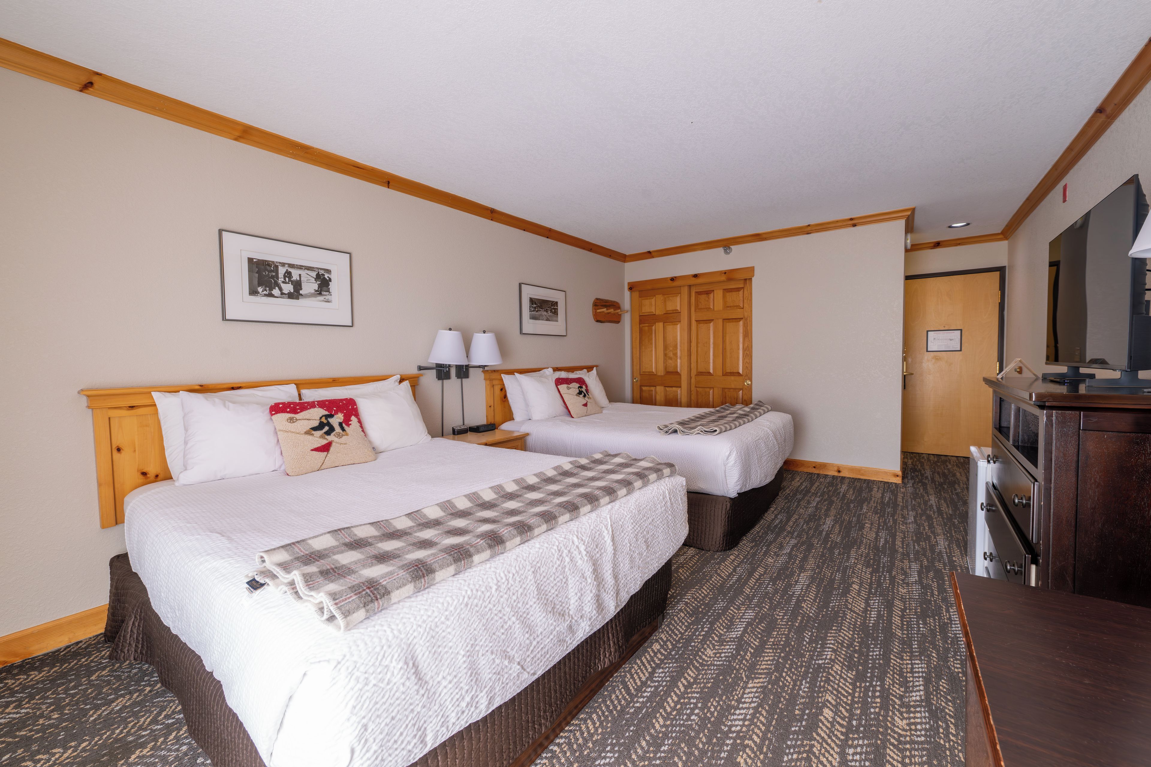 Habitación de hotel con dos camas, un escritorio, un televisor y una puerta.