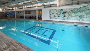 Una piscina interior amb sòl de rajoles i un mural decoratiu gran.