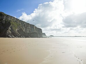 Une plage bordée d’une grande falaise, sous un ciel dégagé.
