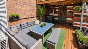 Un patio con un conjunto de sofás, una mesa y plantas en macetas.