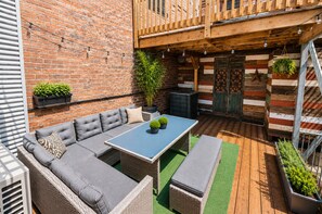 Zona patio con divano, tavolino e piante in vaso.