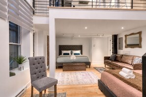 Un interno moderno con un letto, una poltrona grigia, un divano marrone e un grande specchio.