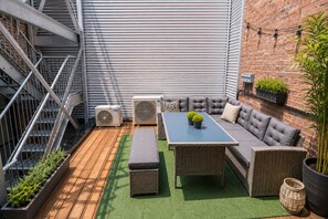 A rooftop patio with a sofa set, a table, and planters.
