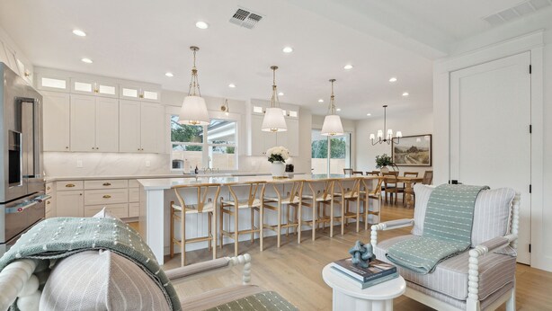 A modern kitchen with white cabinets, a central island, and pendant lighting. There are wooden chairs and a dining table in the adjacent dining area. - Luxury Villa with Huge Kitchen/ Hot Tub/ Barrel Sauna (Boerne)