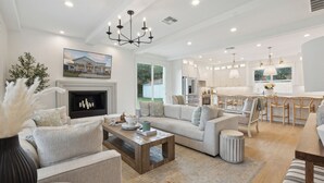 A spacious living room with a fireplace, a dining area with a large table, and a kitchen with modern appliances. - Luxury Villa with Huge Kitchen/ Hot Tub/ Barrel Sauna (Boerne)
