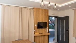 Ein modernes Zimmer mit einer Holzwand, einem Flachbildfernseher, einem Holztisch und einer zur Außenwelt führenden Tür.