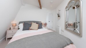 Une chambre à coucher avec un lit, des tables de chevet, un miroir et un radiateur.
