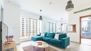 Ein modernes Wohnzimmer mit einem türkisfarbenen Sofa, einem Holztisch und großen Fenstern mit Blick auf die Stadt.