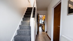 A staircase leading to a kitchen area with a wooden floor and white walls. - Spacious 4 Bed with Free Parking (Southampton)