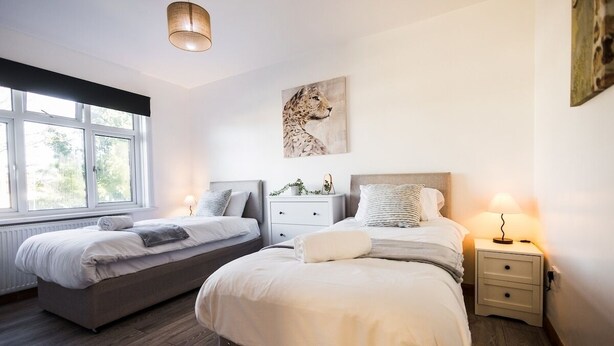 A modern bedroom with two beds, a large window, and a leopard artwork on the wall. - Spacious 4 Bed with Free Parking (Southampton)