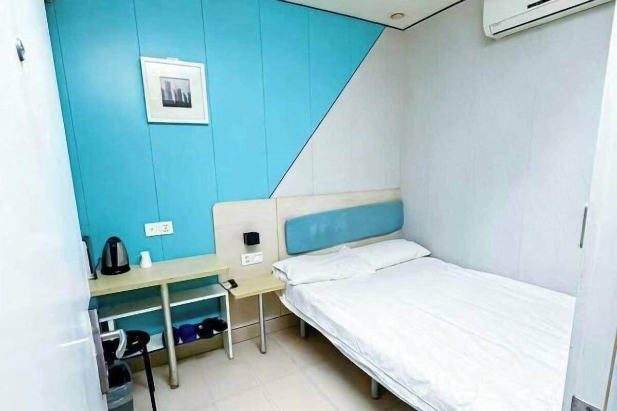 Una habitación de hotel pequeña y funcional con una cama individual, un escritorio y una silla.