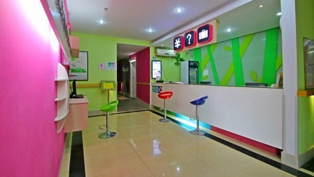 A brightly colored reception area with a counter, a green wall, and a pink wall. - 100 Inn Shanghai Songjiang Xincheng Subway Station (Shanghai)