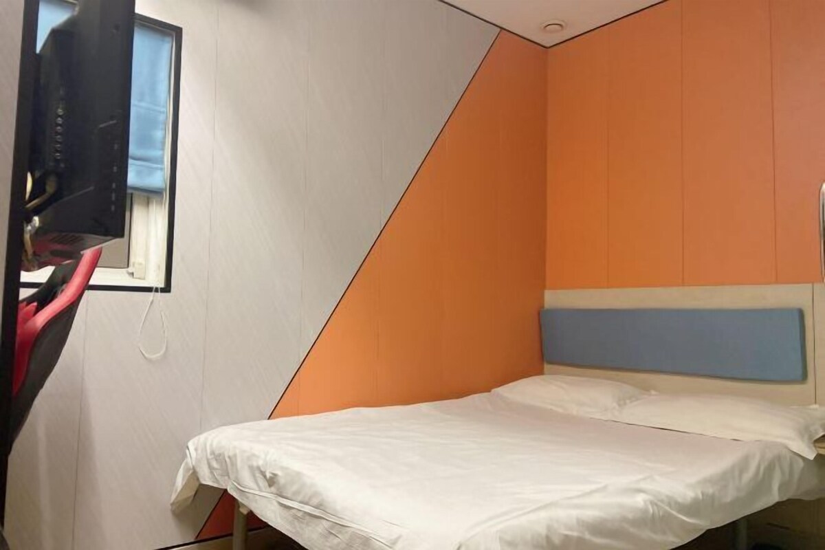 A small, single-bed room with a slanted ceiling and a window.