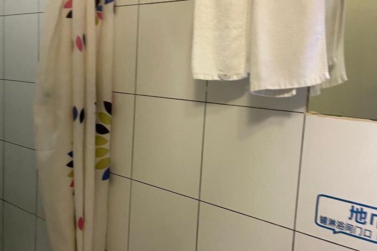 A tiled bathroom with a shower curtain and a towel hanging on the wall.