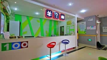 A reception area with a counter, a green wall, and a sign with symbols.