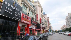 A street view with various commercial buildings, including a hotel with a prominent sign. - 100 Inn Shanghai Songjiang Xincheng Subway Station (Shanghai)