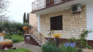 A two-story house with a stone facade, a balcony with metal railings, and a small garden with flowers and plants. - ROSANNA 2 Studio with Balcony (Rovinj)