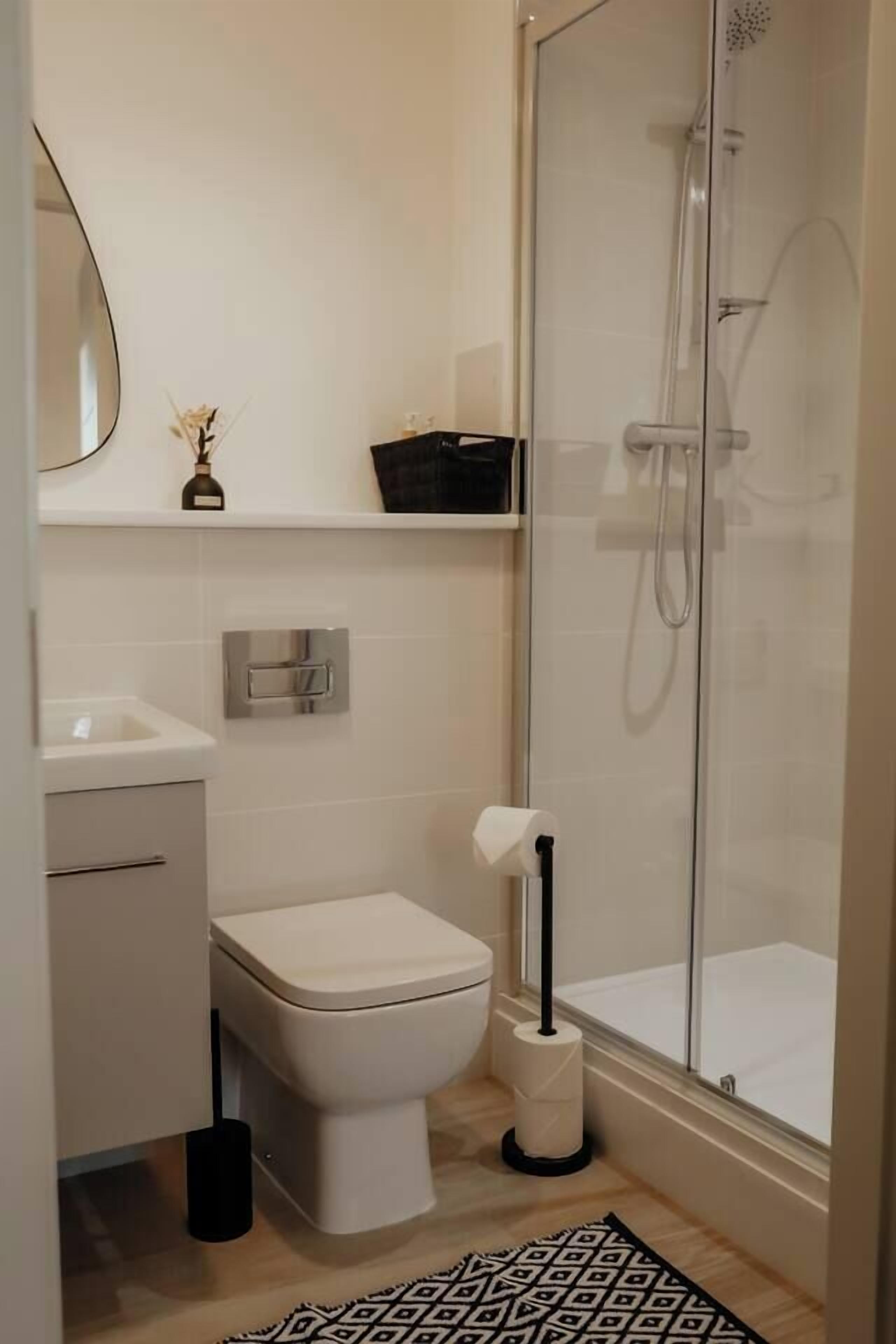 A modern bathroom with a toilet, sink, and shower.