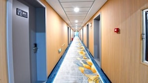 A long, narrow hotel corridor with wooden paneling on the walls, a blue carpet with a yellow and white design, and a sign indicating room number 211. - City 118 Express Hotel (Penglai Scenic Area Bathing Beach Branch) (Yantai)