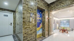 A modern hotel lobby with marble walls, a reception desk, and a seating area with a coffee table. - City 118 Express Hotel (Penglai Scenic Area Bathing Beach Branch) (Yantai)
