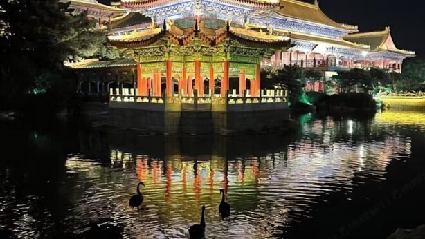 Un edificio chino tradicional con arquitectura ornamentada y su reflejo en el agua.