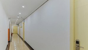 A long, narrow hallway with a tiled floor, a door with a keypad lock, and a light switch on the wall. - Haoting hotel (Shanghai Xincun Road Subway Station) (Shanghai)