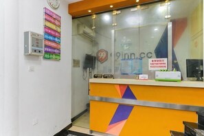 A reception desk with a glass partition, a clock, and a sign with the number 99.
