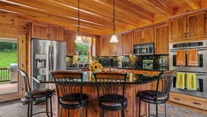 A modern kitchen with wooden cabinets, stainless steel appliances, and a bar area with stools.