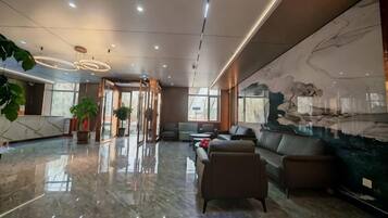 A modern lobby with a marble floor, seating area, and a large abstract art piece on the wall.